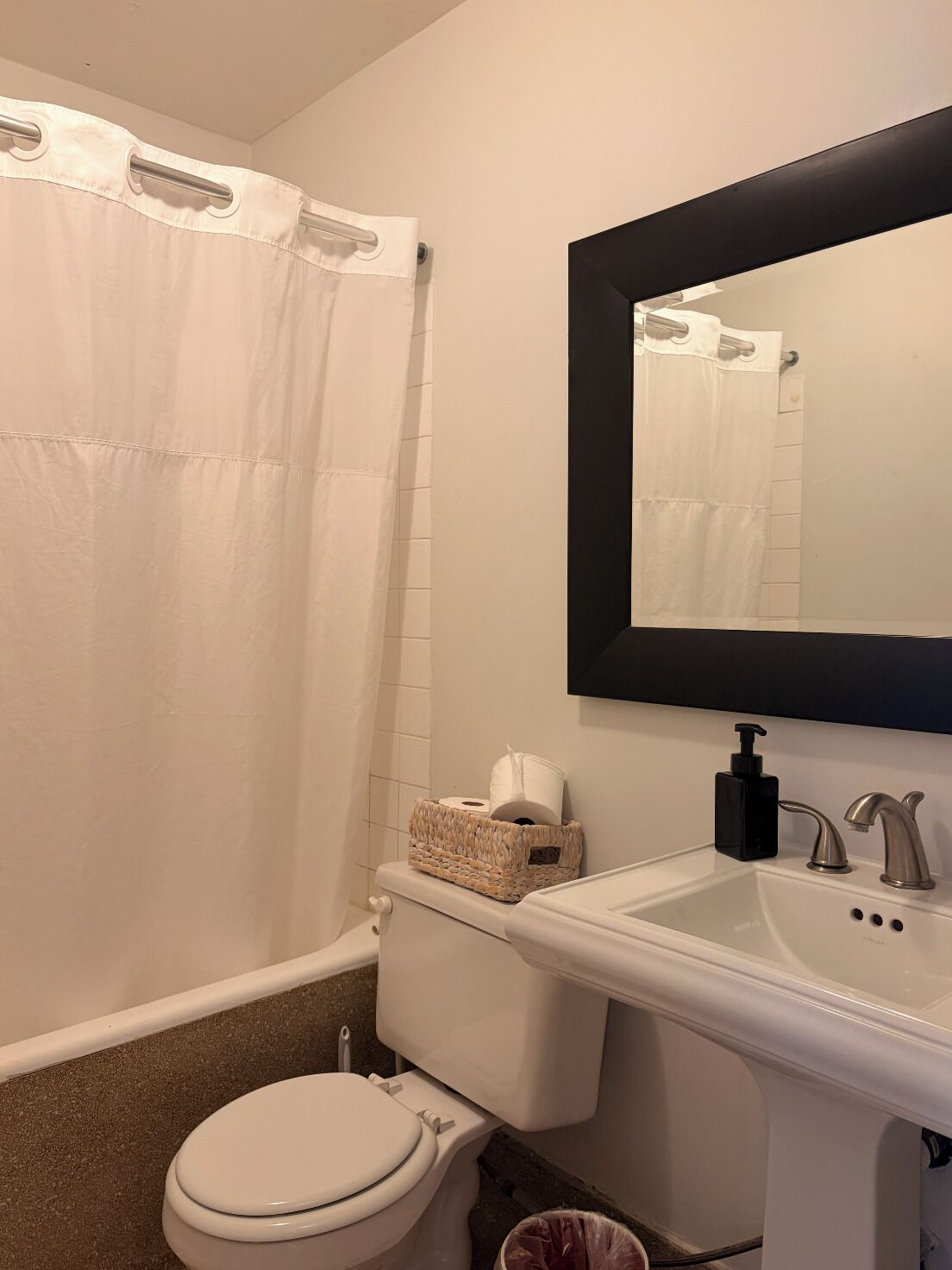 A bathroom with a toilet, sink, and mirror.