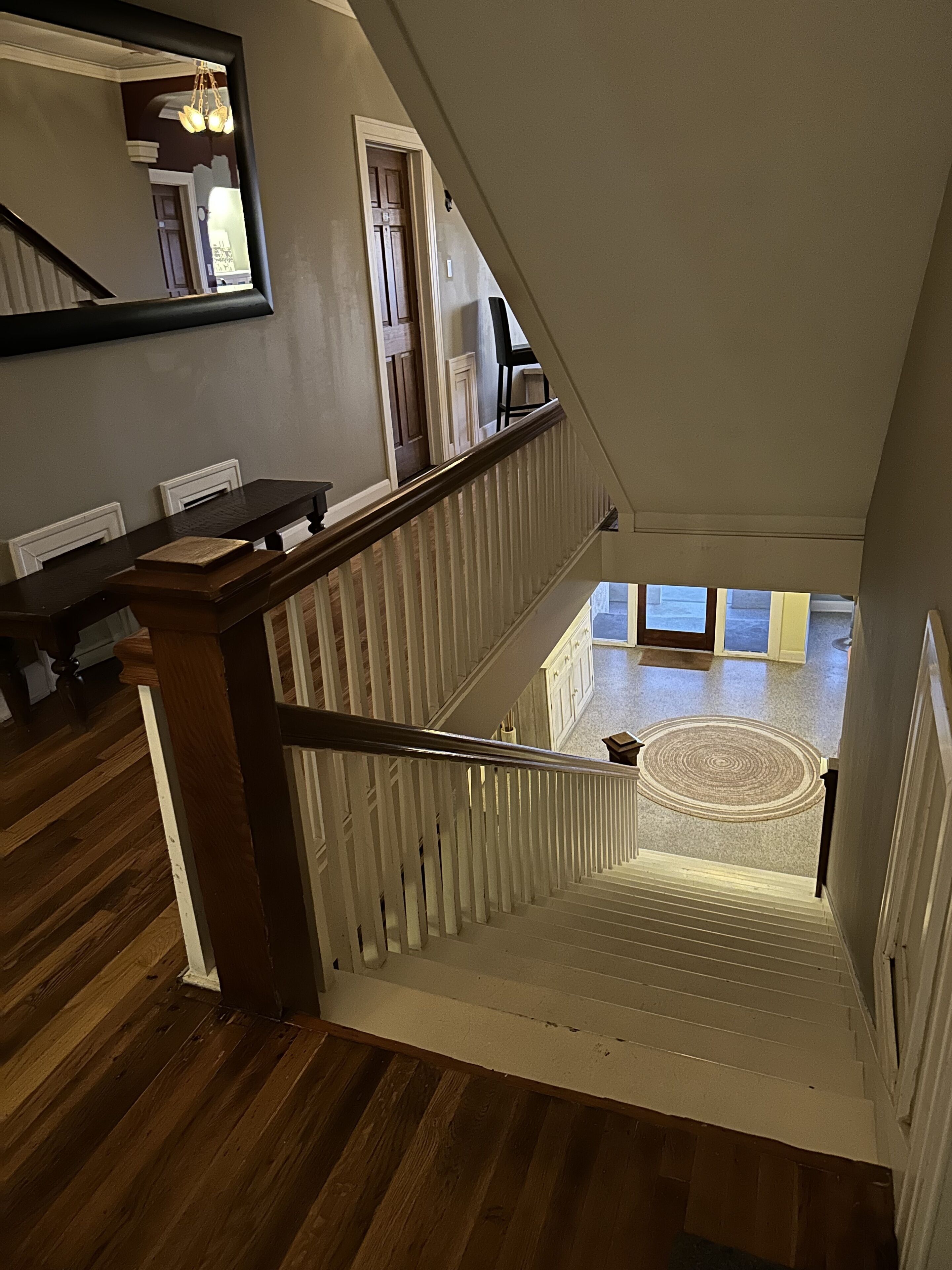 Eine Treppe mit hölzernen Geländern und einem weißen Geländer, die zu einer Empore mit einem runden Teppich f ührt.
