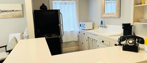 A kitchen with a stove, microwave, sink, and a vintage telephone.