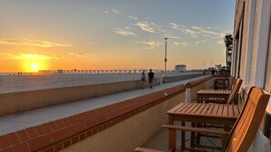 A seaside promenade with wooden benches, a brick wall, and a pier in the background. - The Vurpillat Beachfront Hotel (Hermosa Beach)