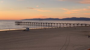 A beach with a long pier extending into the water, a sandy shore, and distant mountains. - The Vurpillat Beachfront Hotel (Hermosa Beach)