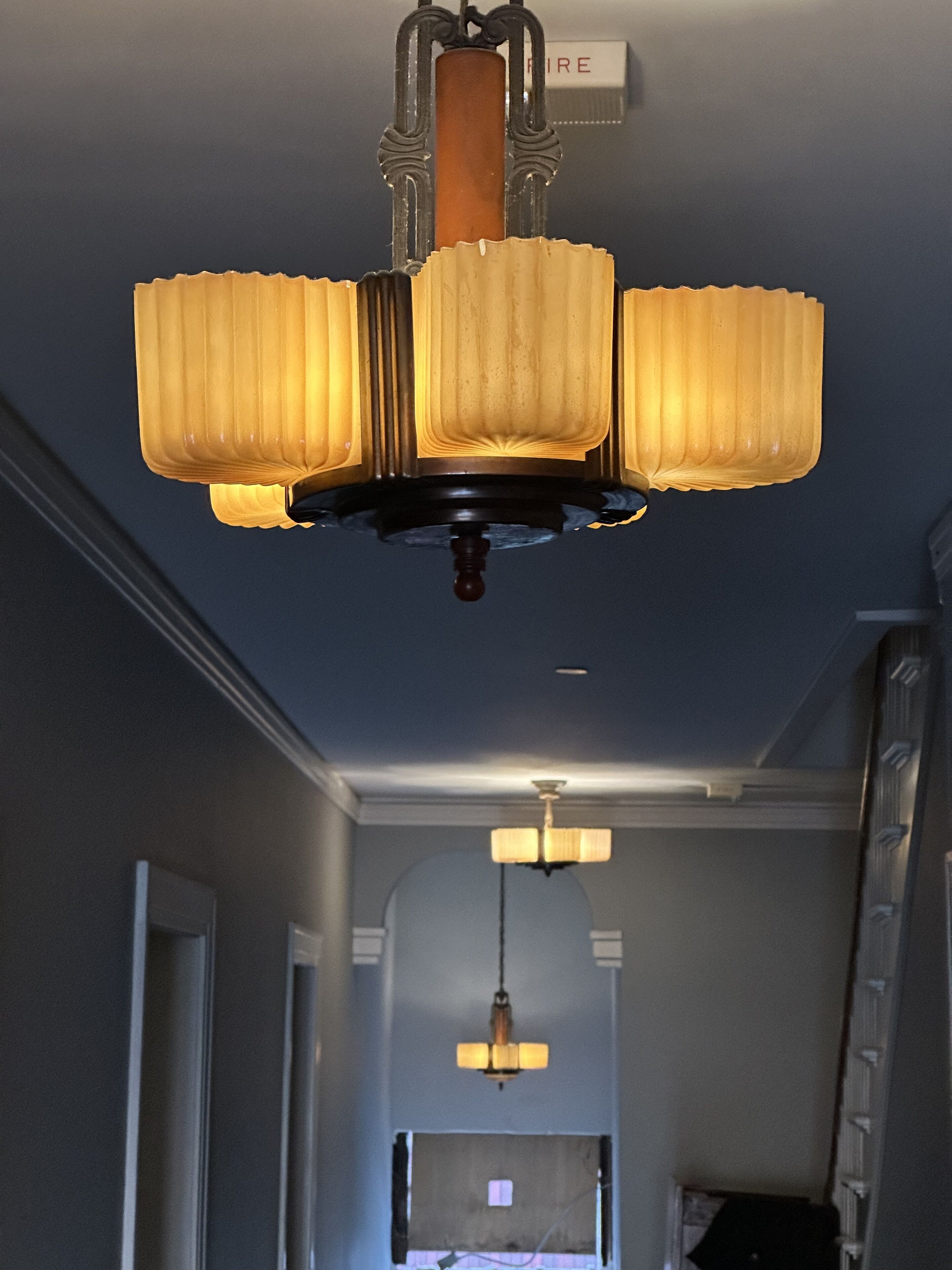 Un candelabro con tres lámparas en un pasillo.