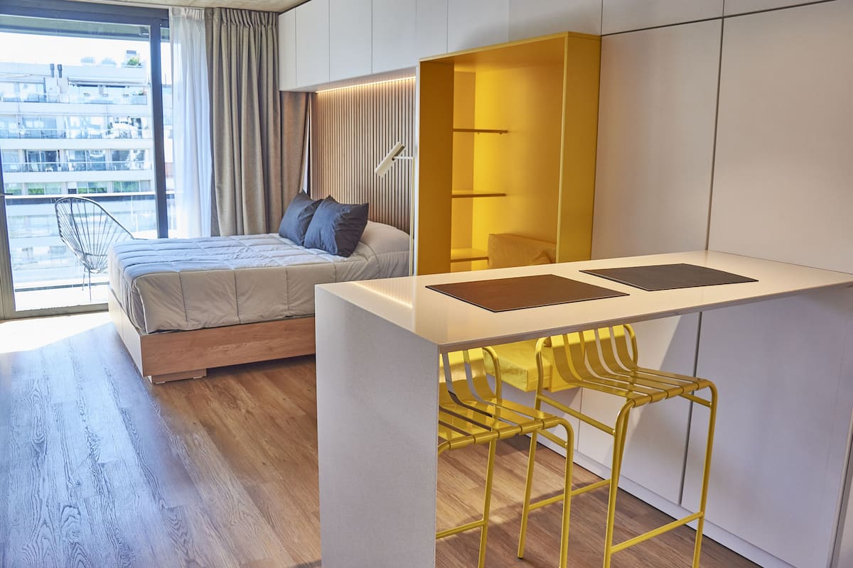 A modern bedroom with a bed, a desk, and a yellow chair.