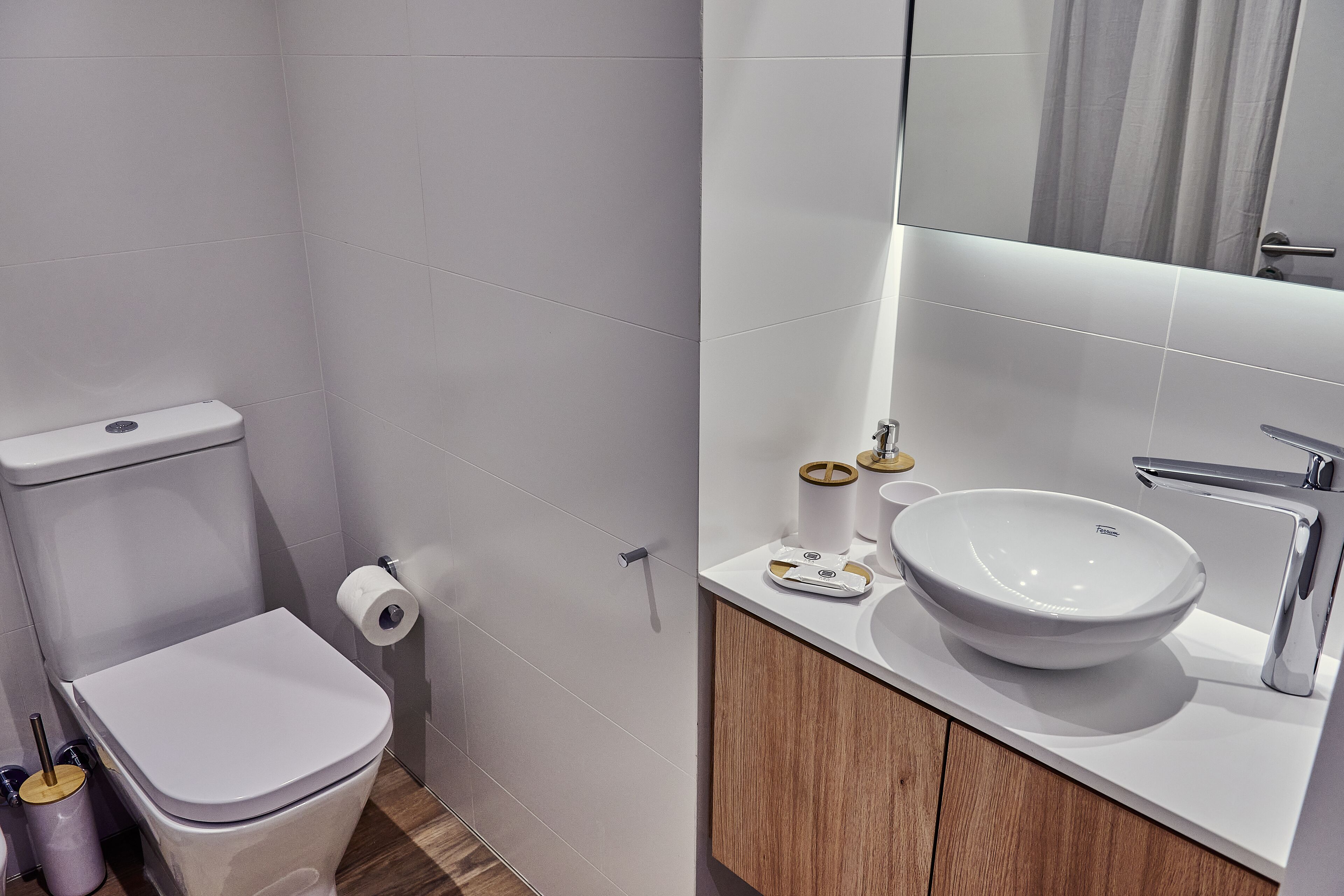 Ein modernes Badezimmer mit Toilette, Waschbecken und Spiegel.