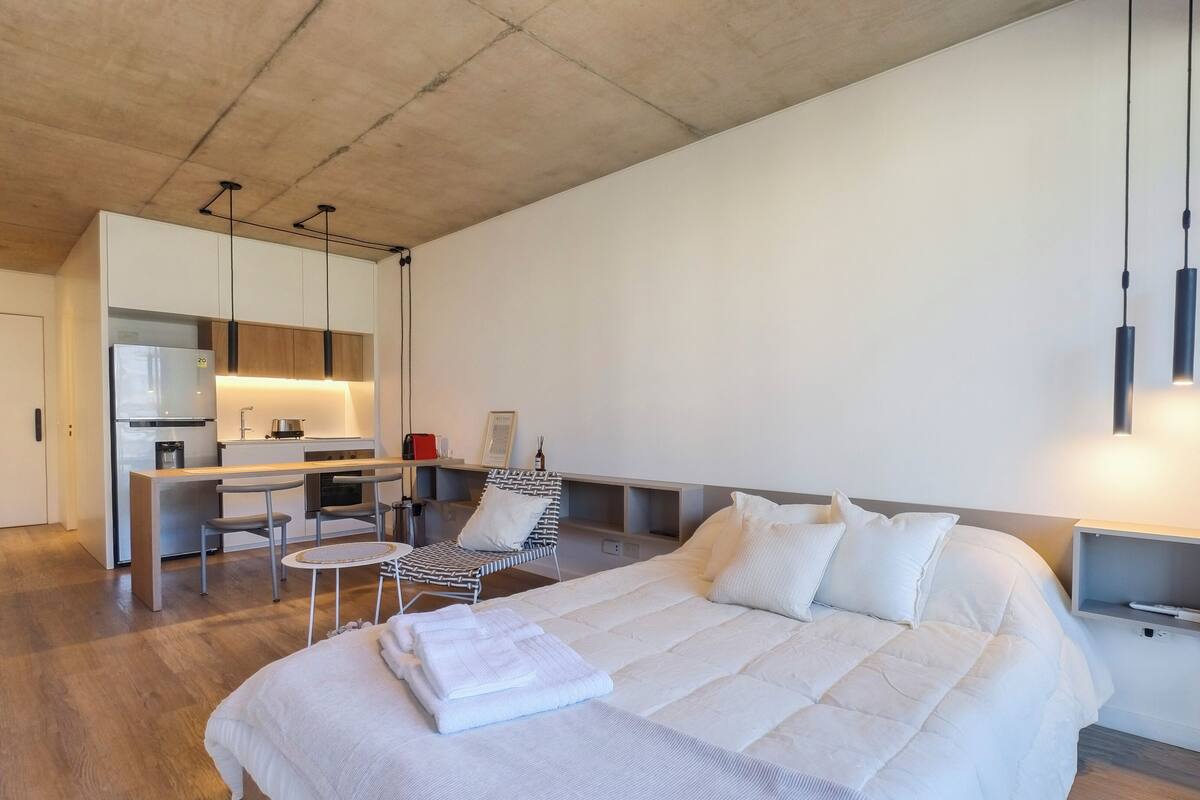 A modern hotel room with a large bed, a desk, and a chair.