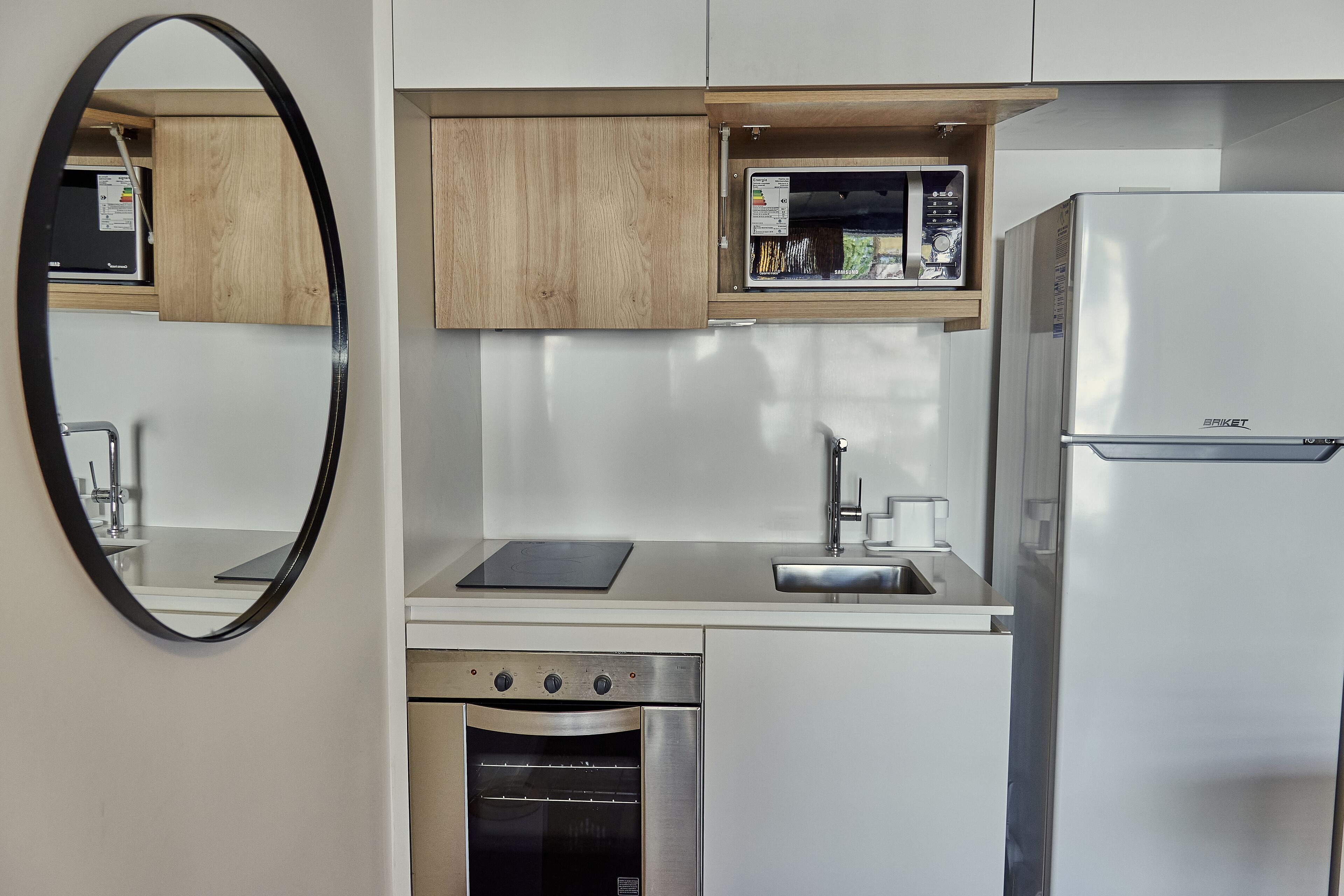 Une cuisine compacte dotée d’un micro-ondes, d’un four et d’un évier intégrés.
