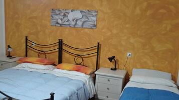 Une chambre à coucher comprenant un lit, deux tables de chevet, une commode, une lampe et une œuvre d’art accrochée au mur.