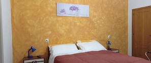 A bedroom with a bed, two bedside tables, a lamp, a wall-mounted picture, and a wooden wardrobe. - Piccola Siesta b&b (Montepulciano)