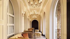 Un hall d’entrée luxueux, agrémenté d’un lustre, d’un espace salon et de grandes fenêtres.