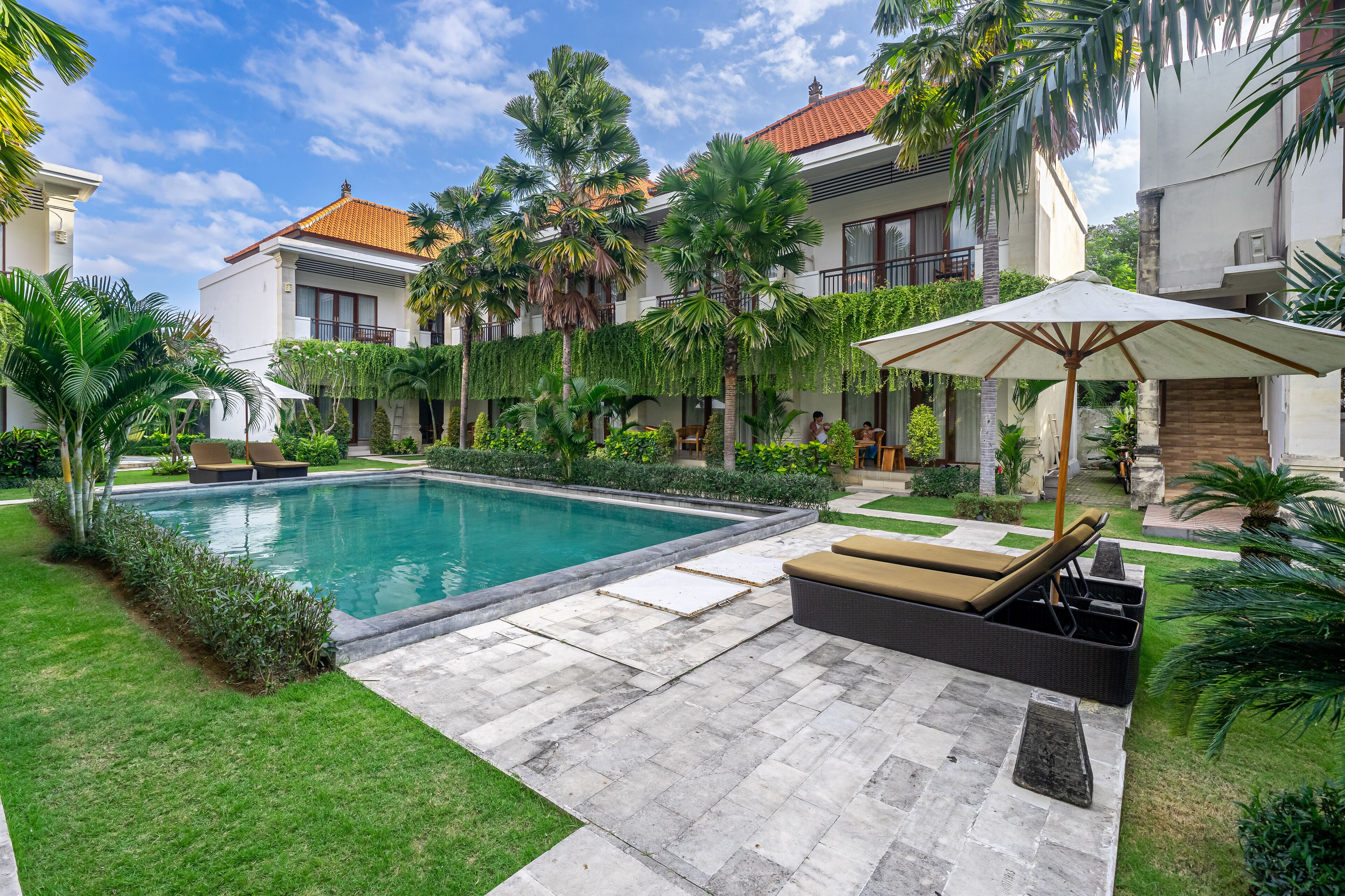 A poolside area with a lounge chair, a sun umbrella, and a well-maintained garden.
