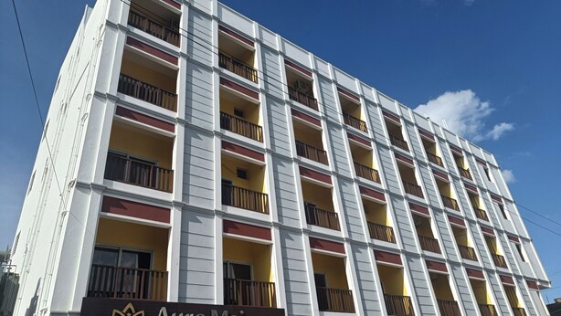 A multi-story hotel with balconies, a prominent 'Auro Maison' sign, and a clear blue sky in the background. - Hotel Auro Maison (Puducherry)