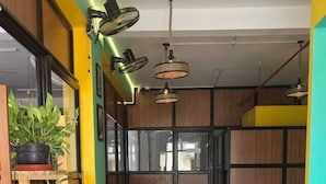 A modern interior with a clean, minimalist design, featuring a dining area with white furniture and a variety of potted plants. - Hotel Auro Maison (Puducherry)