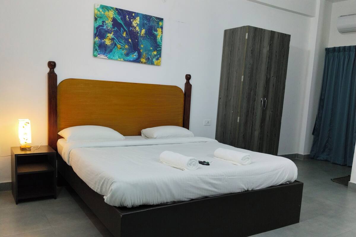 A neatly made bed with white linens, a wooden headboard, and a bedside table with a lamp.