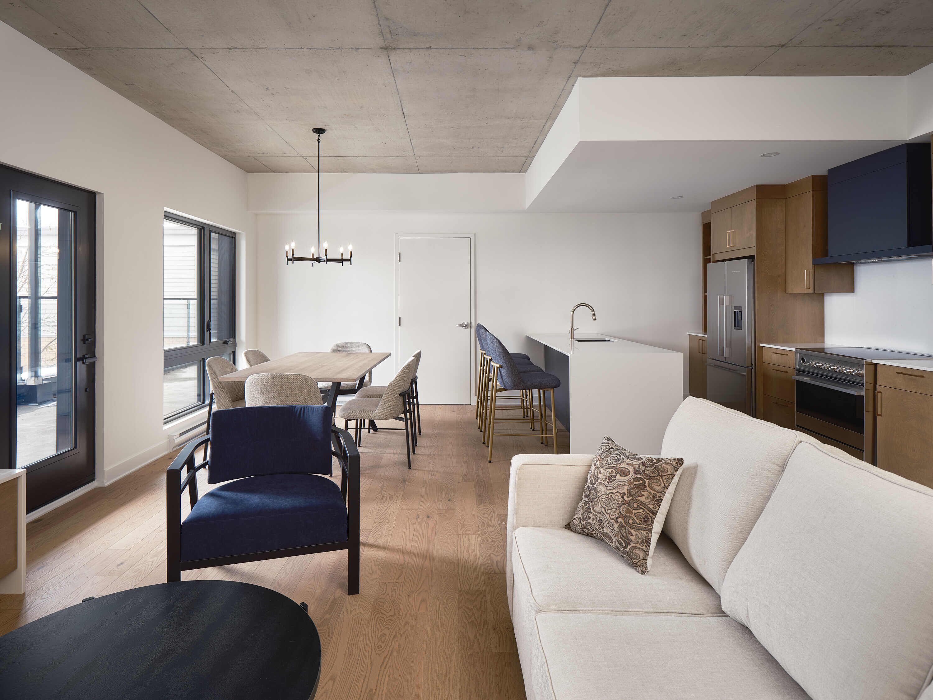 Un appartement moderne comprenant un coin repas, une cuisine et un salon.