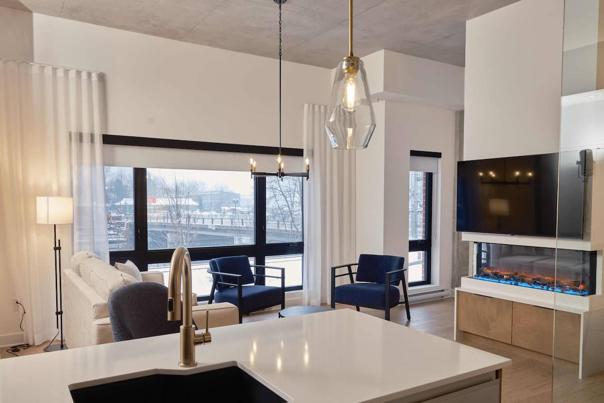 A modern kitchen with a white countertop, a built-in sink, and a large window offering a view of the city.