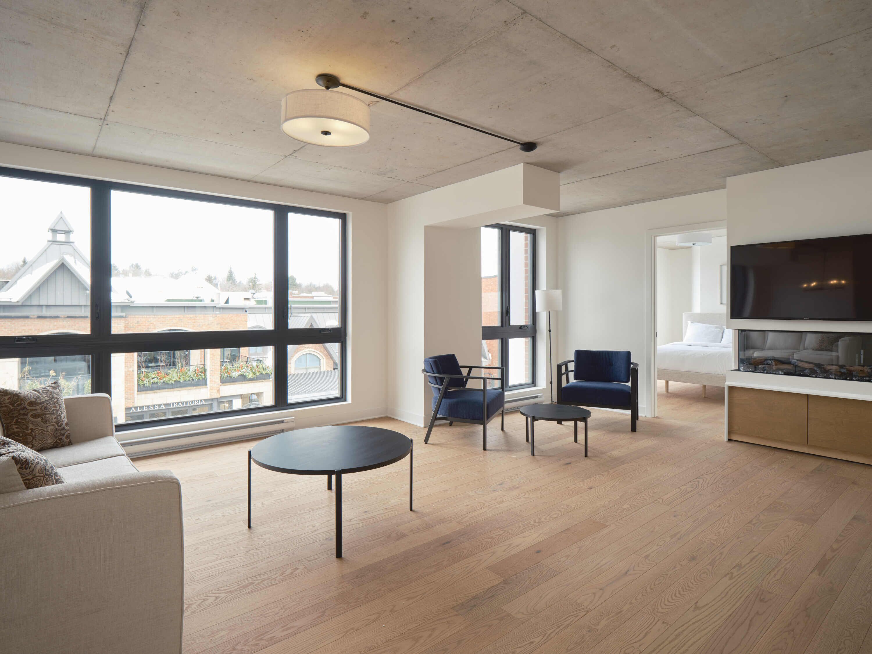 A spacious living room with large windows, a sofa, a coffee table, and a TV.
