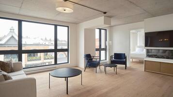 A spacious living room with large windows, a sofa, a coffee table, and a TV.