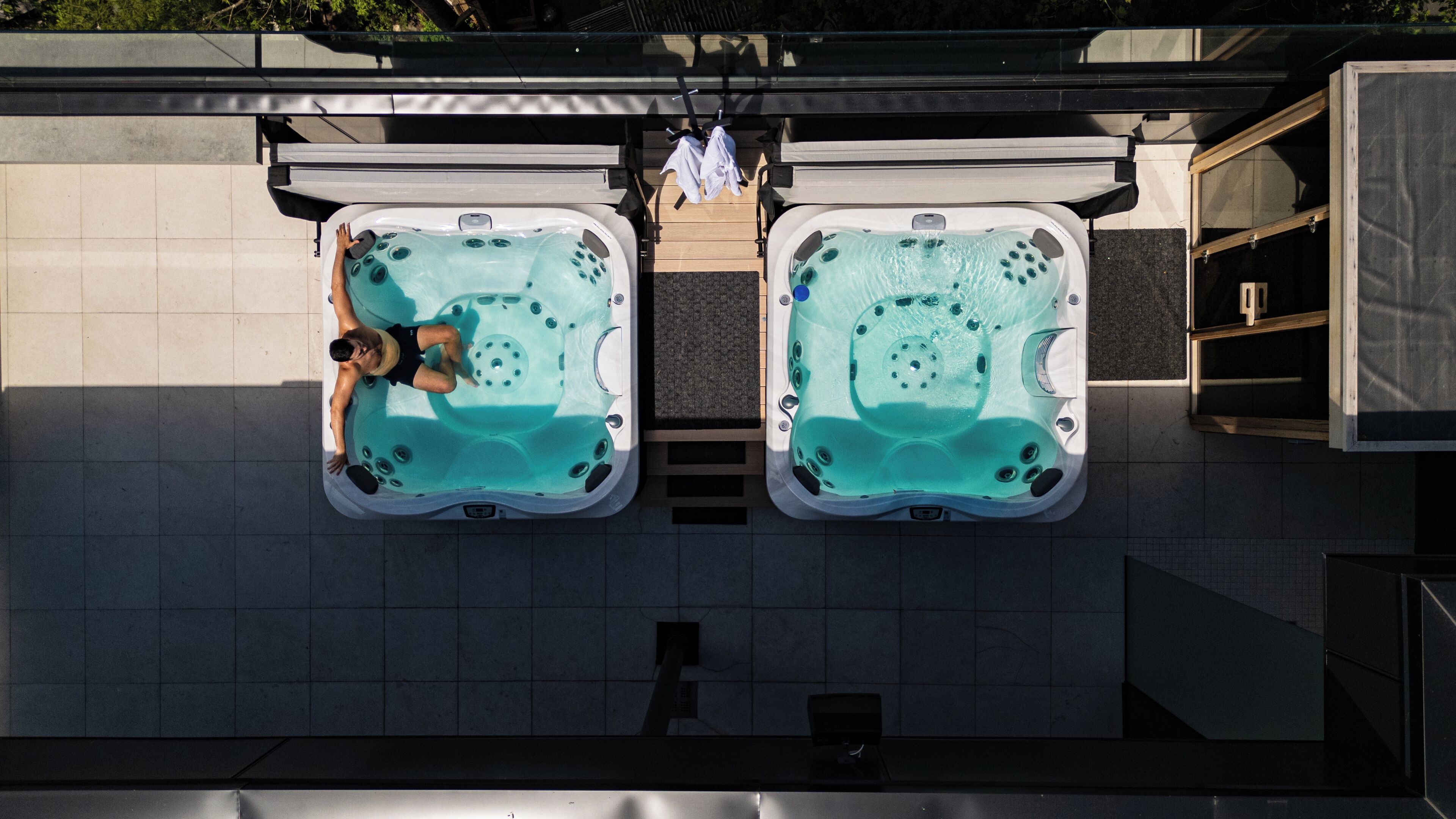 Two hot tubs with a person relaxing in one.