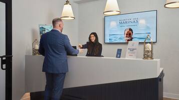 A reception desk with a large screen displaying the hotel name and a welcome sign.