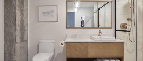 A modern bathroom with a toilet, sink, and shower.
