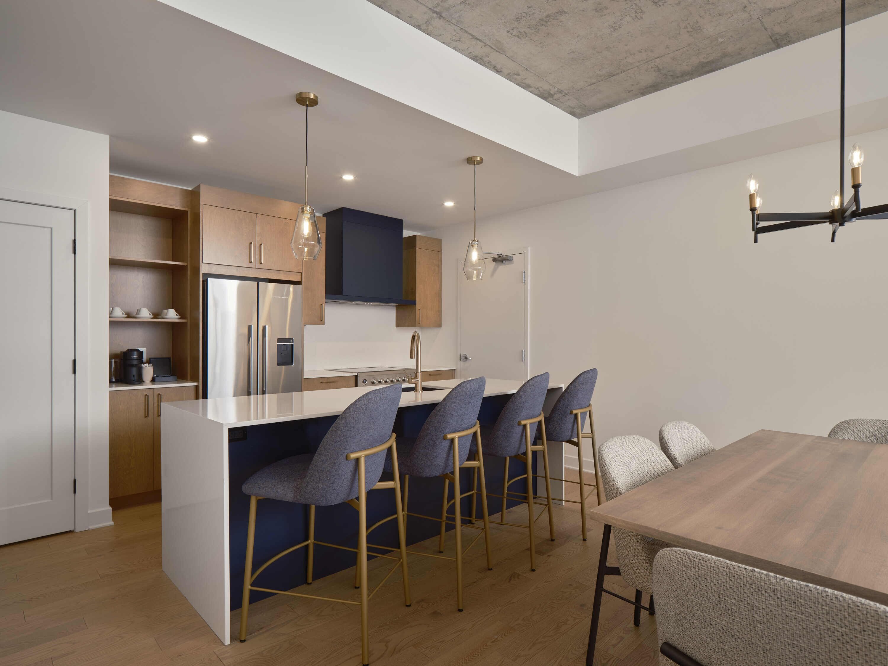 A modern kitchen with a central island, bar stools, and a dining table.