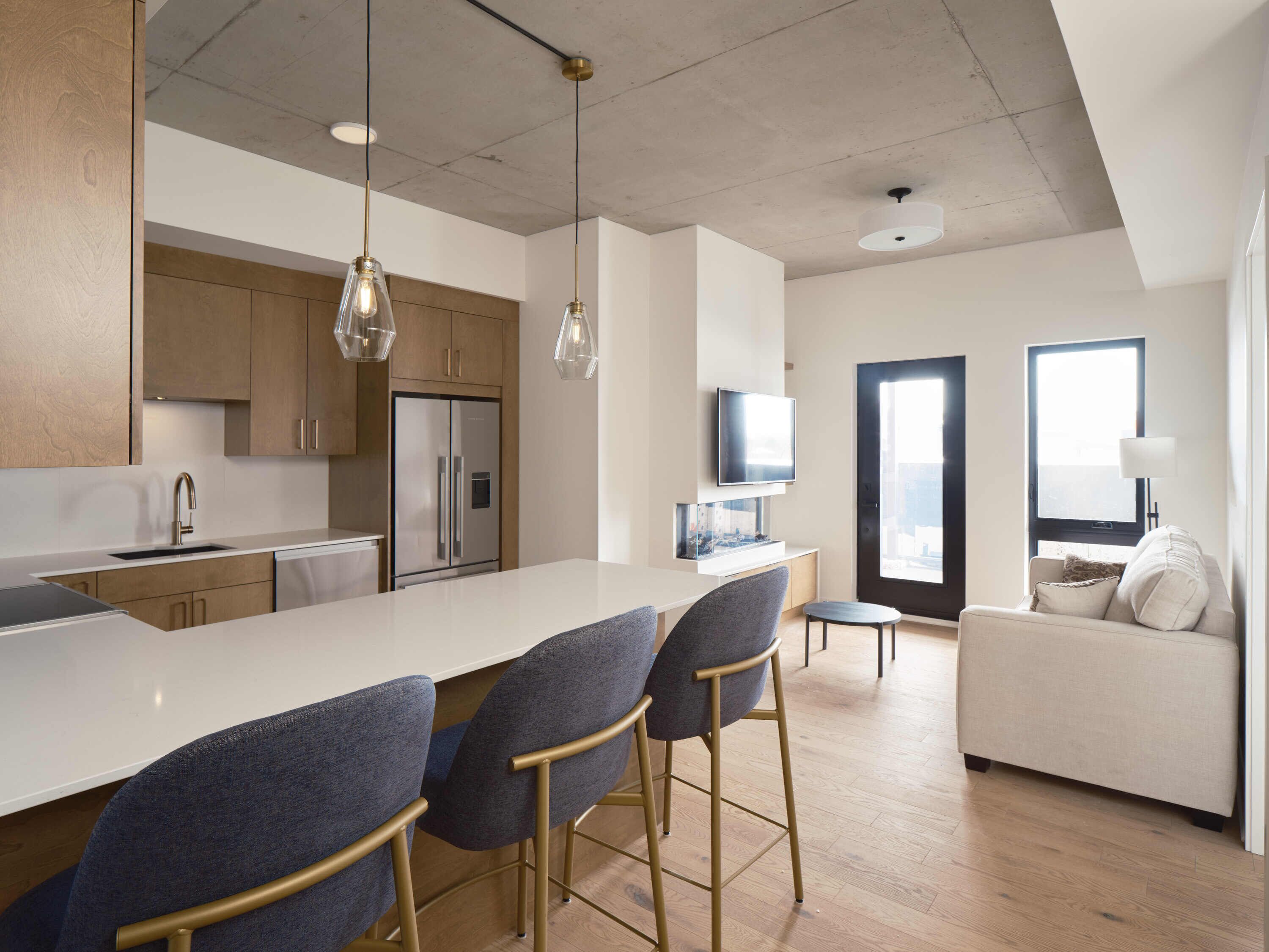 A modern kitchen with a central island, bar stools, and a built-in TV.