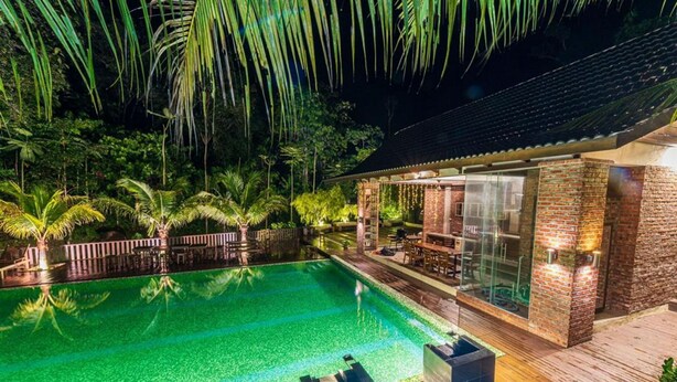 A pool area with a clear water surface, surrounded by palm trees and a wooden deck.