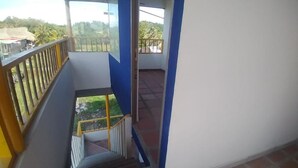 A balcony with a metal railing, a staircase leading to an upper level, and a view of greenery outside. - Punta Antioquia Hotel (San Juan de Urabá)