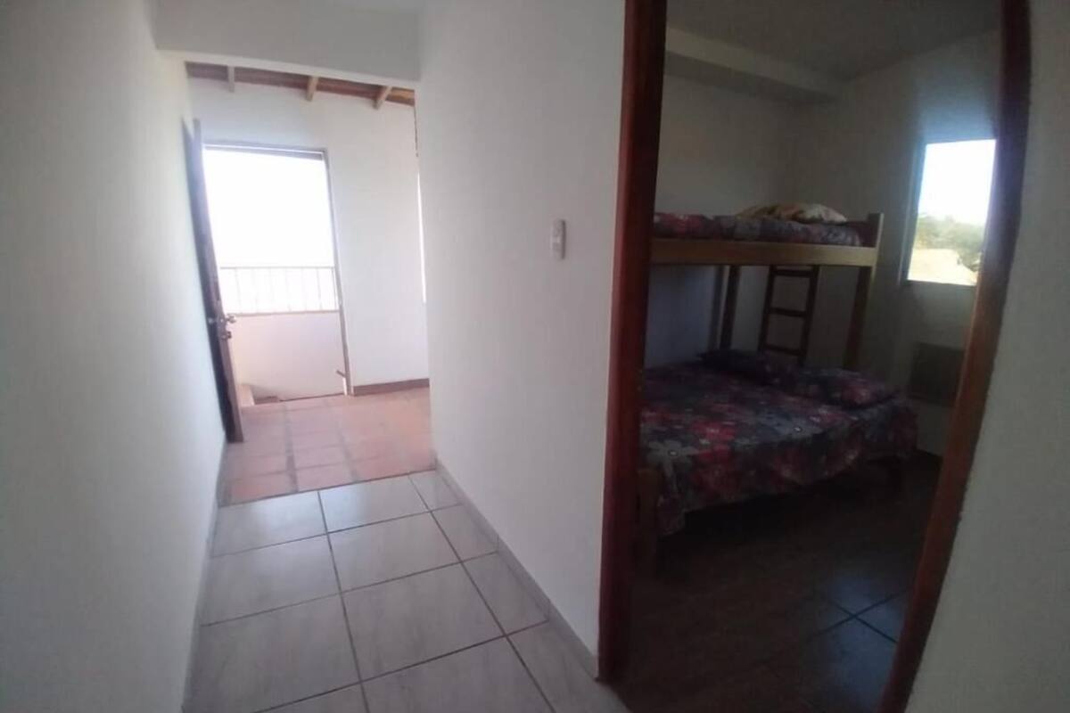 A room with a bunk bed, a tiled floor, a door leading to another room, and a window.