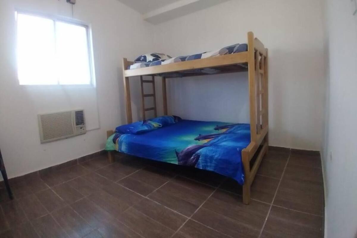 A bunk bed room with a window, air conditioning unit, and tiled floor.