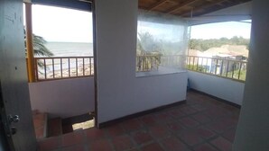 A room with a tiled floor, a balcony with a view of the beach, and a wooden ceiling. - Punta Antioquia Hotel (San Juan de Urabá)