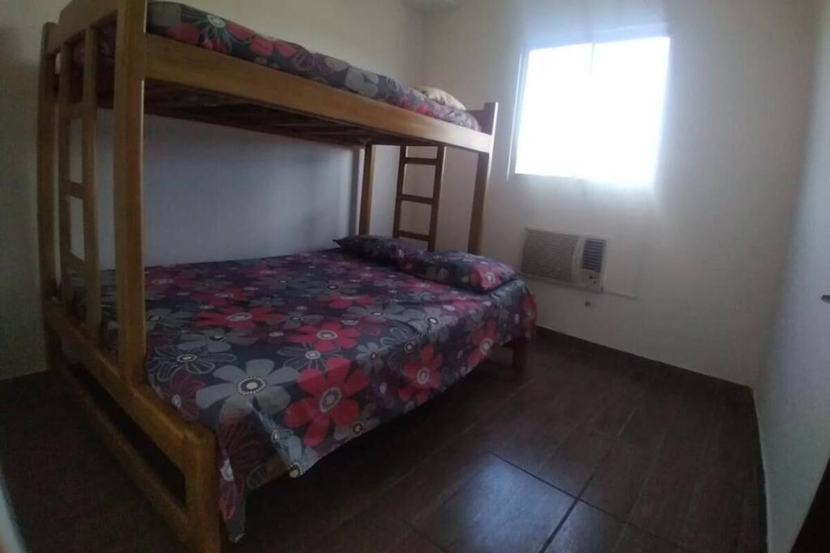 A room with a bunk bed, a window, and a radiator.