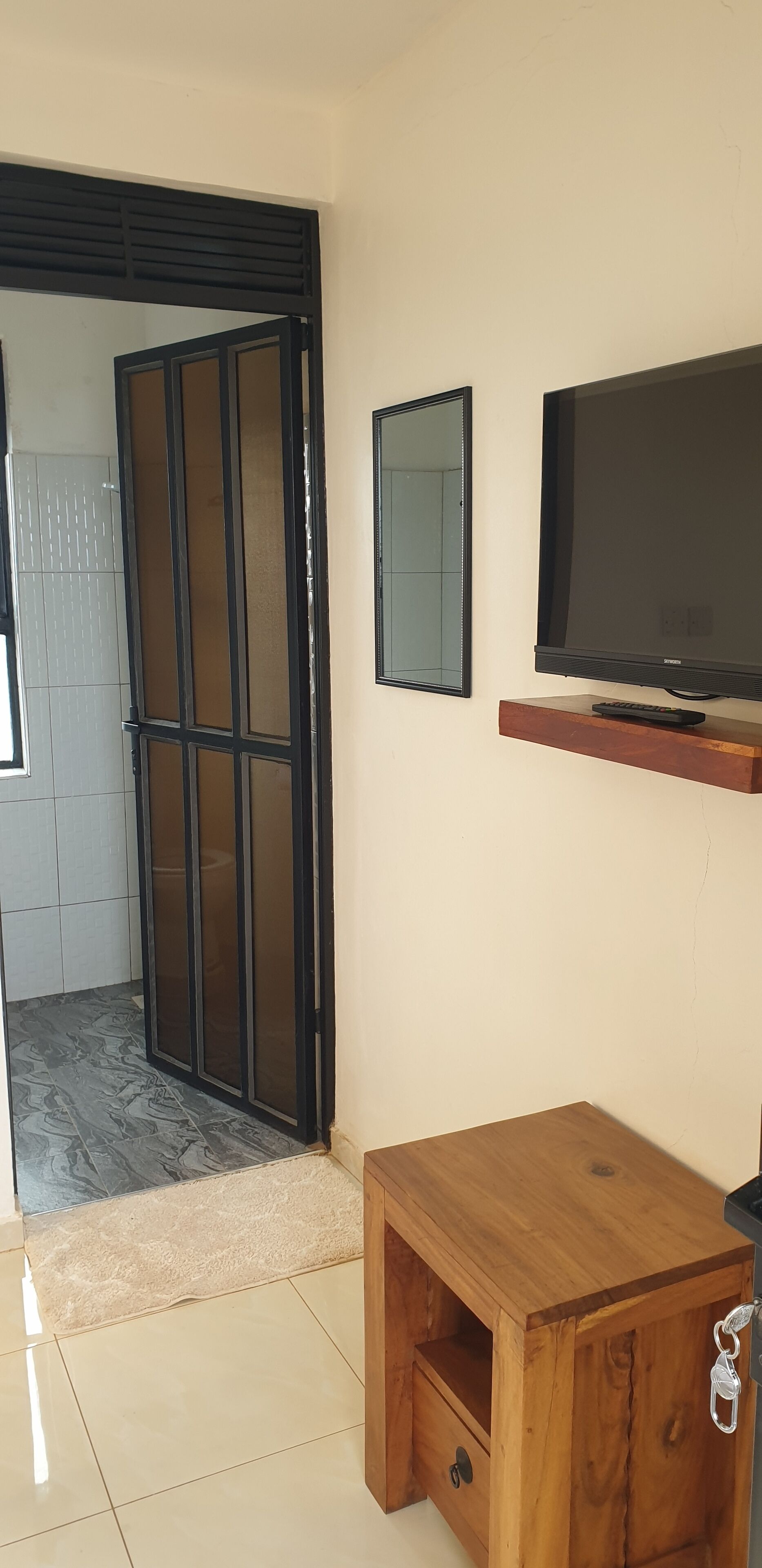 Une pièce dotée d’une porte coulissante, d’un téléviseur posé sur une étagère en bois et d’une petite armoire en bois avec un tiroir.