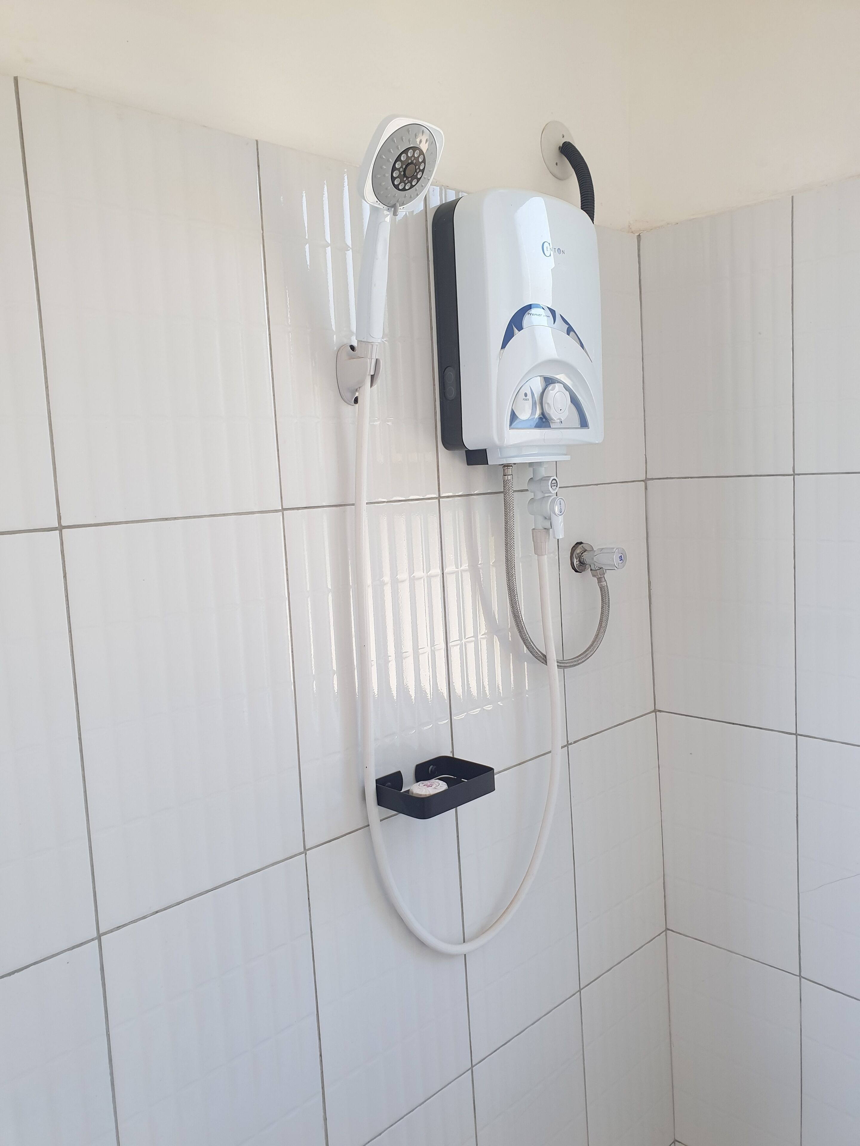 A shower with a handheld showerhead, a wall-mounted control panel, and a handheld shower hose.