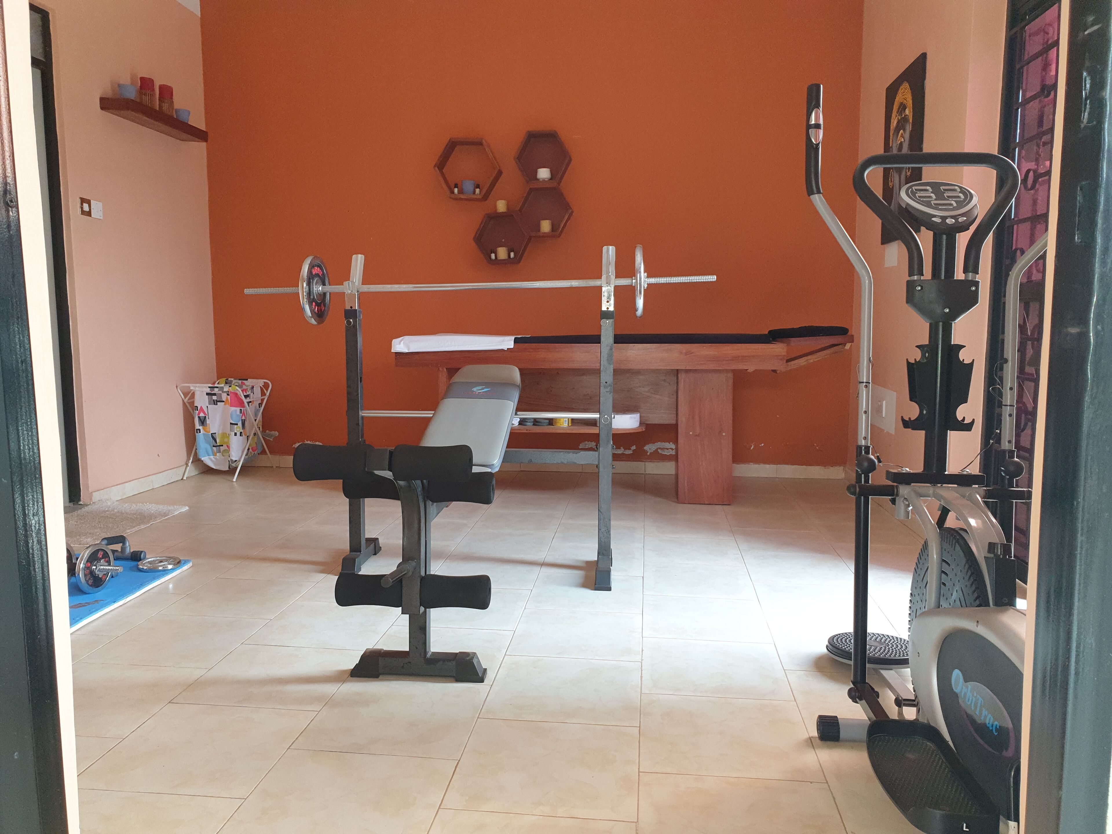 Ein Heimfitnessraum mit einer Hantelbank, einem Squat-Gestell und einem stationären Fahrrad.