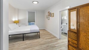 A bedroom with a bed, bedside lamp, and a wooden wardrobe. - The Nighthawk Eyrie (Stanwood)
