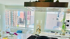 A modern kitchen with a built-in oven and stovetop, a white countertop, and a view of the city through large windows. - Times Square Luxurious Massive 2bed/2bath flat,NYC (New York)