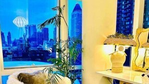 A room with a city view, a chair with a fur throw, a potted plant, a lamp, and a mirror. - Times Square Luxurious Massive 2bed/2bath flat,NYC (New York)