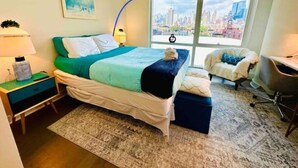 A modern hotel room with a large bed, a desk, a chair, and a view of a cityscape. - Times Square Luxurious Massive 2bed/2bath flat,NYC (New York)