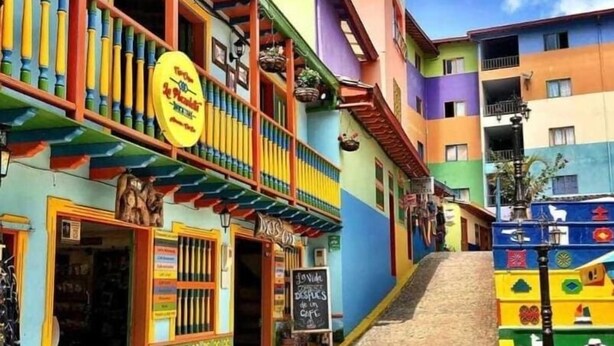 A colorful building with a balcony, a sign for a restaurant, and a staircase leading up to the entrance. - Edificio Avenida Malecon (Guatapé)