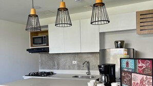 A modern kitchen with a central island, bar stools, and pendant lighting. - Edificio Avenida Malecon (Guatapé)