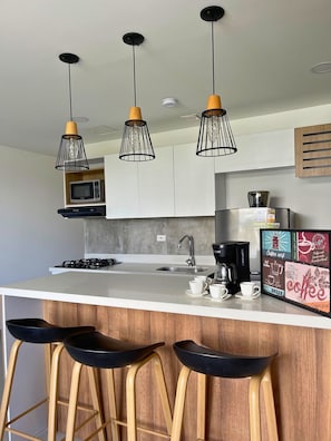 Una cocina moderna con una isla central, taburetes de bar e iluminación colgante.
