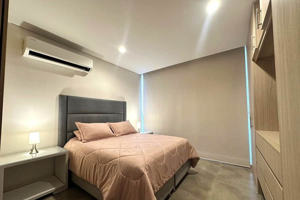 A modern bedroom with a bed, bedside table, and built-in wardrobe.