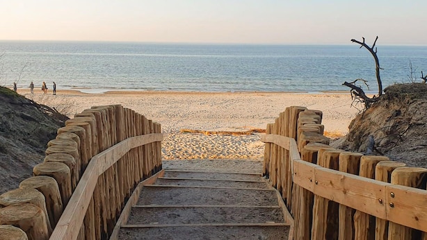 Eine Holztreppe führt zu einem Strand mit freiem Blick auf das Meer.