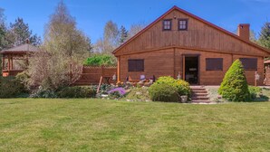 Eine Holzdiele mit einer Veranda, einem kleinen Garten und wolkenlosem, blauem Himmel.