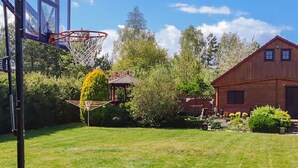 Ein Basketballkorb in einem Hinterhof mit einem Holzstall und einem Garten.