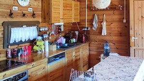 Eine Holzhütte mit einer Küche, Holzschränken, einer Uhr und verschiedenen Küchenutensilien.