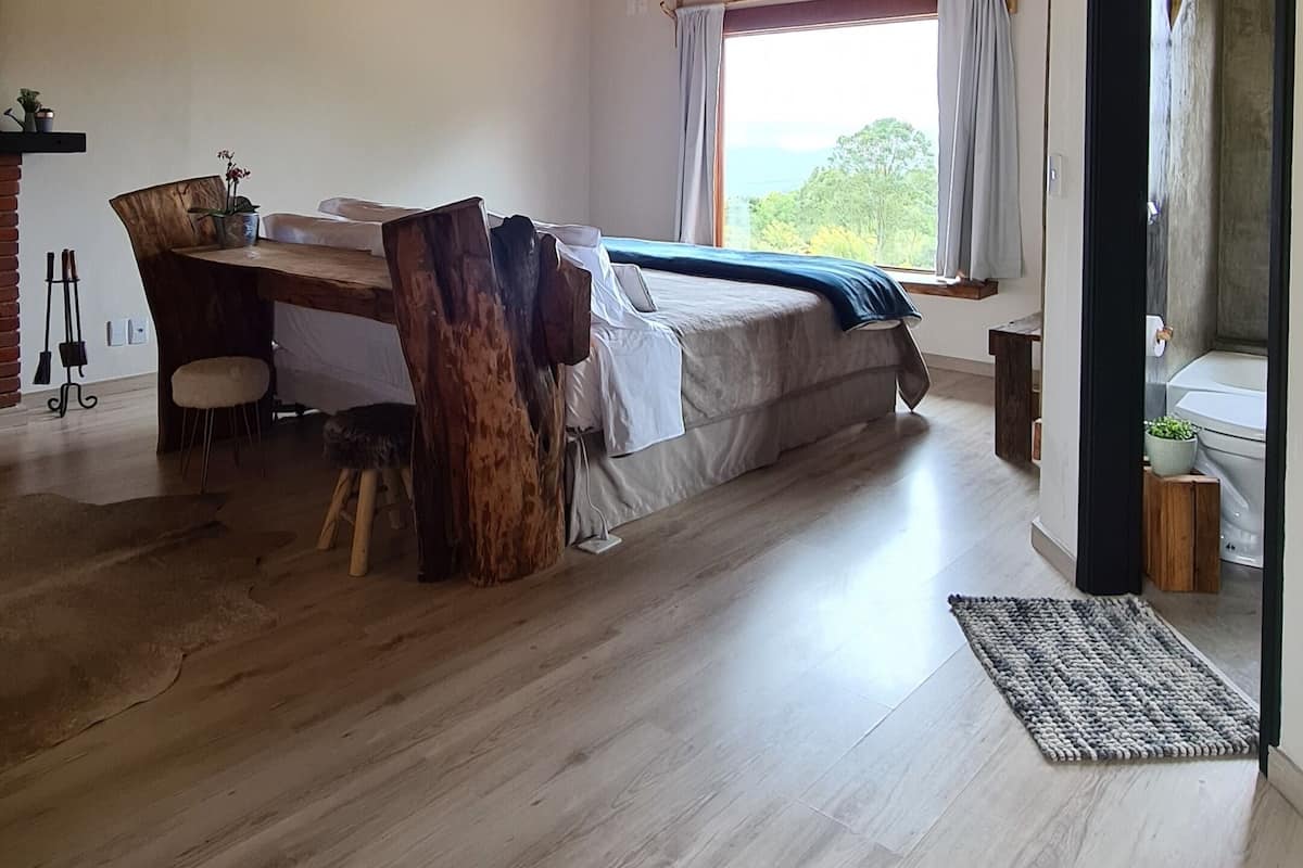 Une pièce spacieuse avec un haut plafond en bois, un lit, une table à manger et une vue sur l’extérieur.