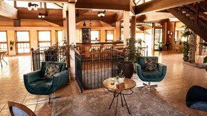 A spacious lobby with wooden beams, a staircase, and a bar area.