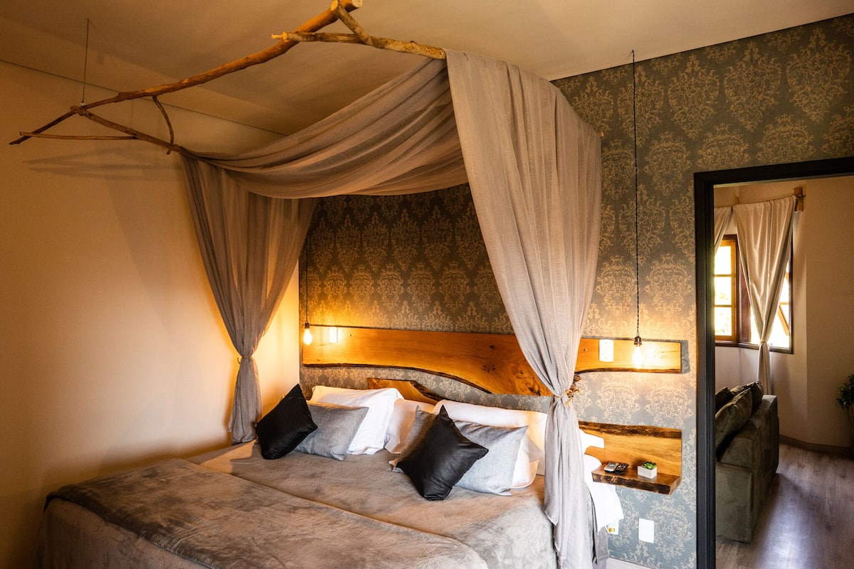 Une chambre à coucher avec un lit à baldaquin, une tête de lit en bois et une table de chevet avec une lampe.